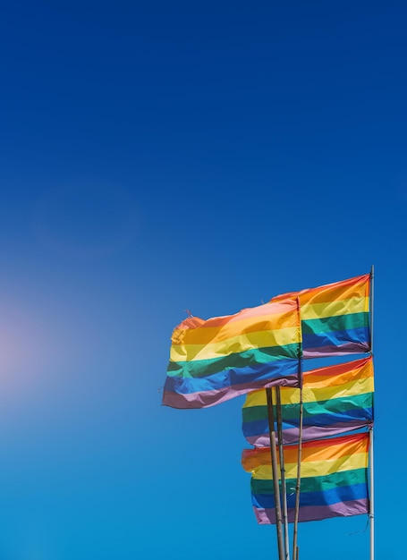 Foto vibranti bandiere dell'orgoglio arcobaleno che sventolano contro un cielo azzurro durante una celebrazione di una giornata di sole