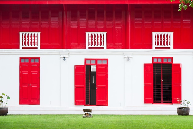 活気に満ちた赤い木製の窓と緑の草伝統的な赤いドアは白い壁タイの古い木製