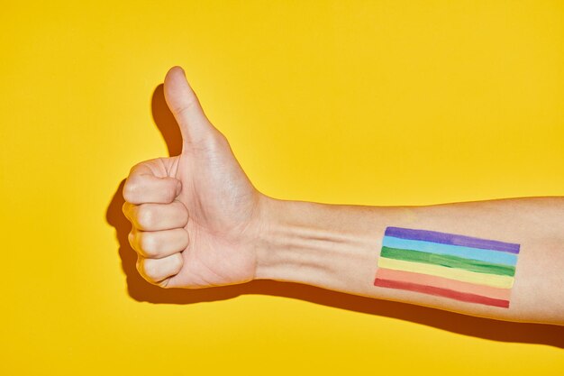 Vibrant shot of arm with rainbow flag tattoo and thumbs up as support symbol for pride month lgbtq