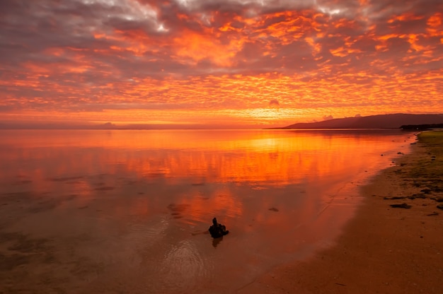 Vibrant sunrise warm colors full of clouds Smooth sea on the beach