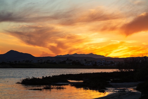 키프로스의 소금 호수 (Larnaca) 에서 활기찬 일몰, 봄에 오렌지색 하늘과 구름