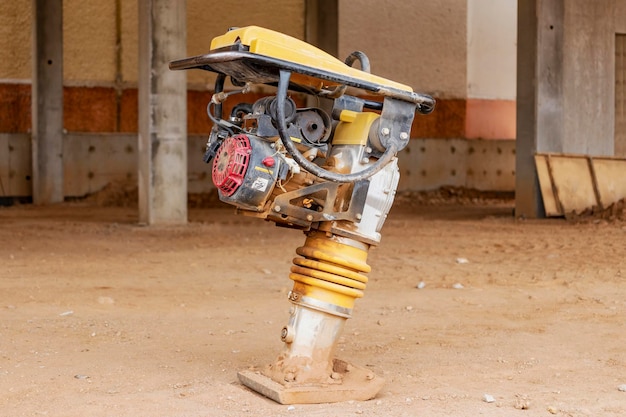 Vibratory rammer with vibrating plate on a construction site Compaction of the soil before laying paving slabs Closeup