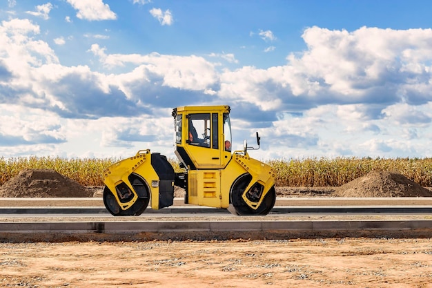 Vibratory road roller lays asphalt on a new road under\
construction closeup of the work of road machinery construction\
work on the construction of urban highways