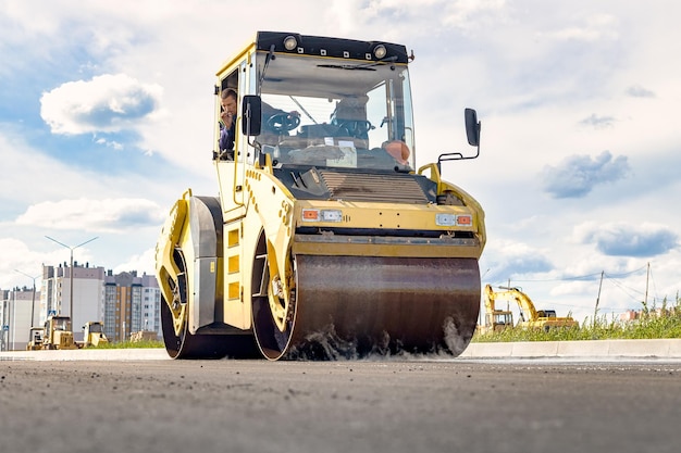 Vibratory road roller lays asphalt on a new road under\
construction closeup of the work of road machinery construction\
work on the construction of urban highways