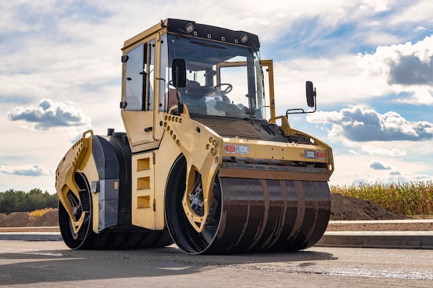 Vibratory road roller lays asphalt on a new road under\
construction closeup of the work of road machinery construction\
work on the construction of urban highways