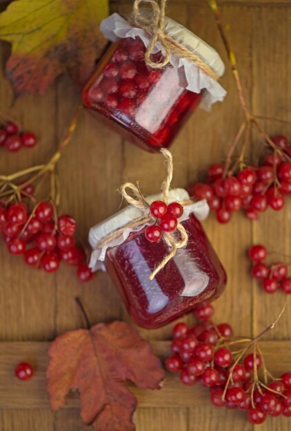 Viburnum fruit jam in a glass jar on a wooden table near the ripe red viburnum berries Source of natural vitamins Used in folk medicine Autumn harvest