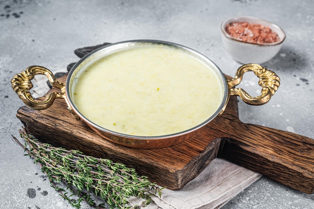 Vichyssoise - traditional French soup made with leek, potato and onion in a pan. Gray background. Top view.