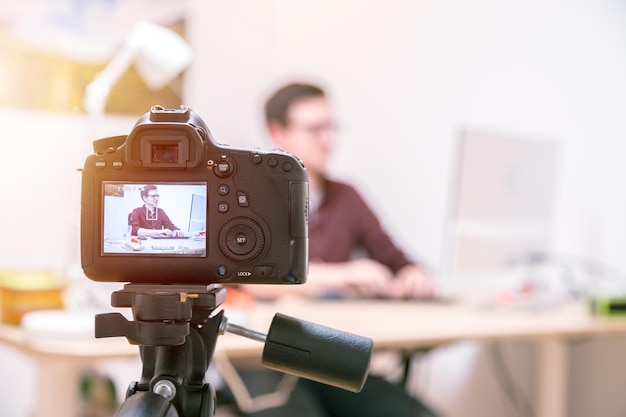 video blogger at home camera on tripod is filming a young man sitting on his working place