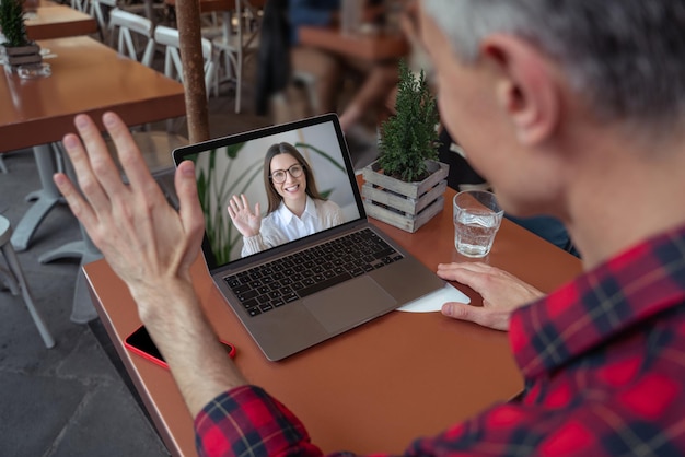 Photo video call. man having a video call in a cafe and waving his hand