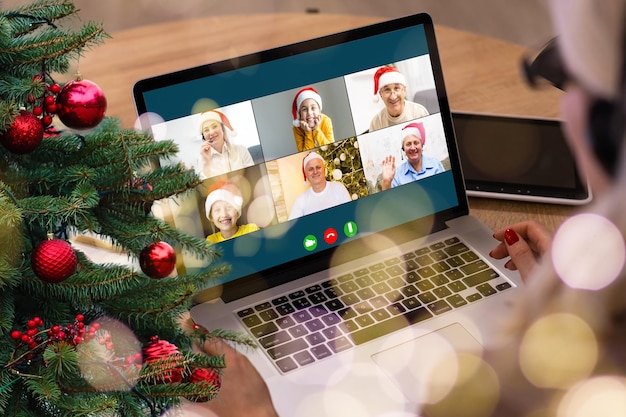 Video call with happy diverse children on laptop computer in his workshop. Self-isolation and virtual online celebration at home concept. Christmas
