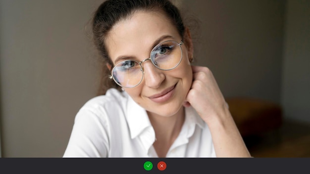 Photo video call a woman with glasses hello gesture looks into the camera smiles