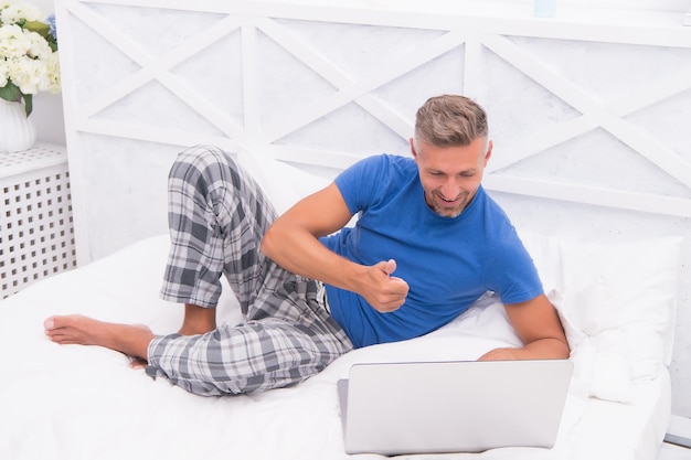 Video call Work from home Mature guy pajamas in bed Businessman with computer Hipster work laptop Bedroom becomes new office Remote job Shopping online Online communication Glad to see you