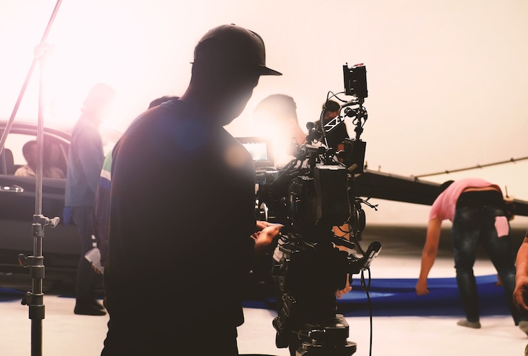 Photo behind video camera in film or movie production on tripod and professional gear which shooting