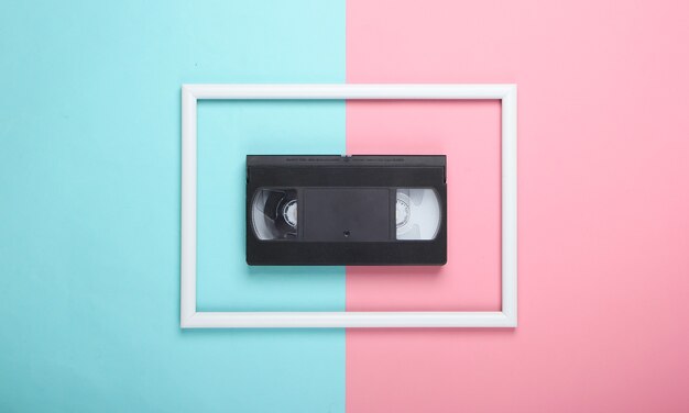 Video cassette on pink blue pastel surface with white frame