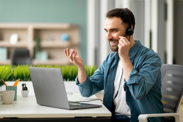 Video conference male office employee in headset having web call on laptop