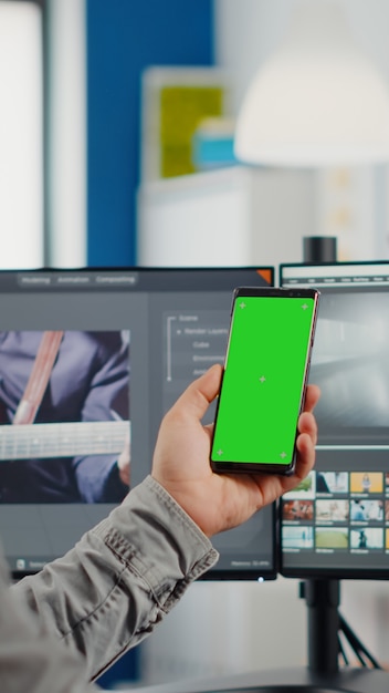 Photo video editor talking on video call holding smartphone with green screen