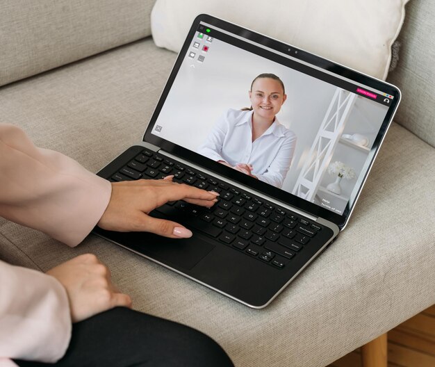 Video-interview Virtuele vergadering Webconferentie Vrolijke zakenvrouw die vanuit huis werkt, bespreekt samenwerking met vrouwelijke partner op laptopscherm op bank in digitaal kantoor