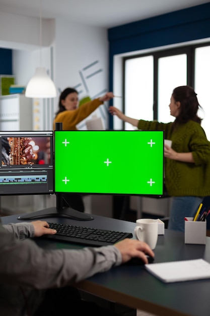 Photo video maker editor editing movie project using post production software working in post production agency at pc with green screen, chroma key, mock up isolated display. man processing audio montage