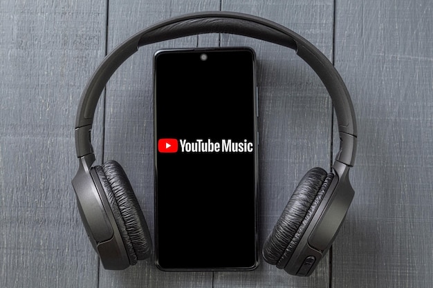 Video player on mobile phone screen and wireless headphones on dark background