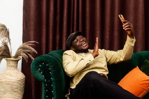 Videobellen als een jonge zwarte Afrikaanse man die lacht en zwaait naar de mobiele telefoon in de hand in een kleurrijk huis