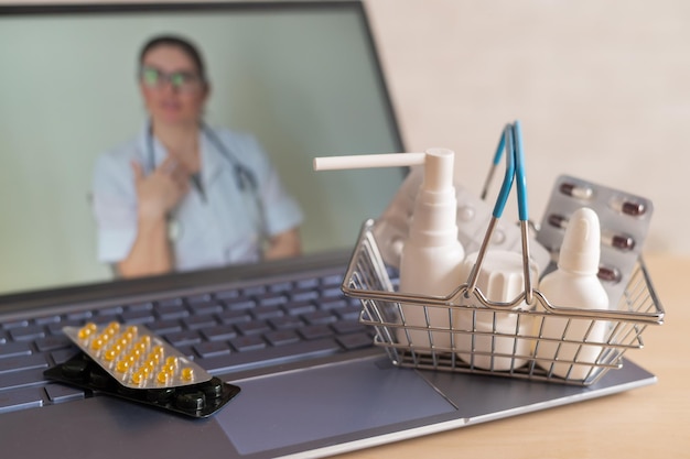 Foto videoconferentie met een arts op een laptop en tablet in een klein winkelmandje online apotheek apotheker op een computerscherm