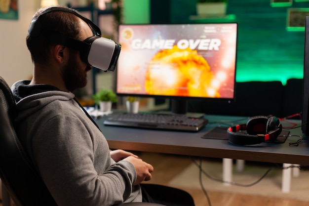 Videogamespeler verliest space shooter-competitie terwijl hij een virtual reality-headset draagt. Verslagen gamer met professionele console voor online toernooi 's avonds laat in de gameroom