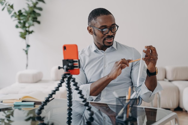 Videogesprek op telefoon Afro-freelancer heeft online brainstorm Gelukkige man toont papierwerk met gegevens