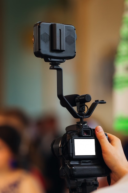 Videographer shooting video with dslr camera. Detail of professional camera equipment. Cameraman Adjusting Camera