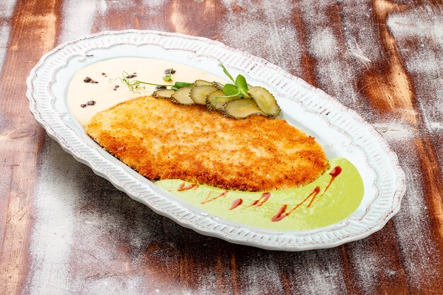 Viennese chicken schnitzel with sauces and pickles Haute cuisine On a wooden background