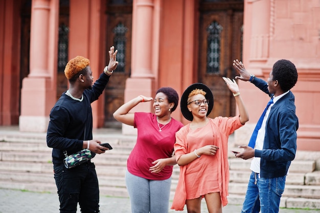 Vier Afrikaanse vrienden die buiten plezier hebben Twee zwarte meisjes geven high five aan jongens