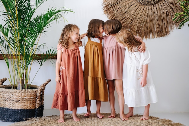 Foto vier blootsvoetige vriendinnen van 6 jaar oud in mooie jurken zijn aan het gekken en maken grappen.