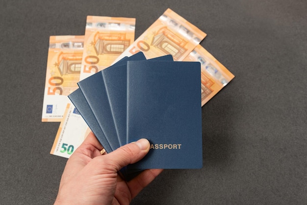 Vier blucovered paspoorten in man hand op euro cash achtergrond Paspoort met lege omslag op geld achtergrond