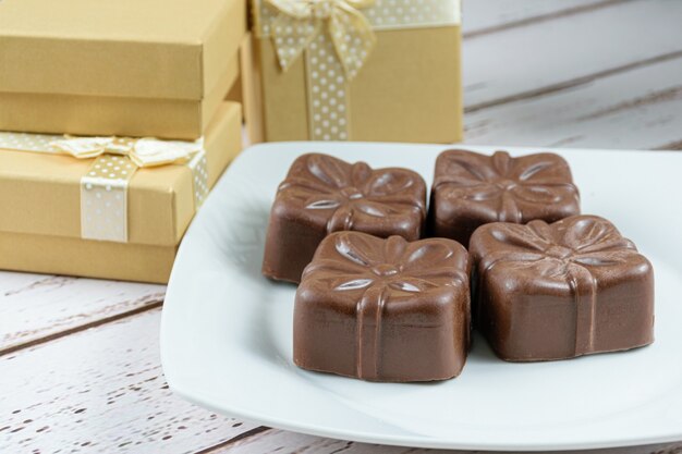 Vier Braziliaanse honingkoekjes naast gouden geschenkdozen (zijaanzicht).