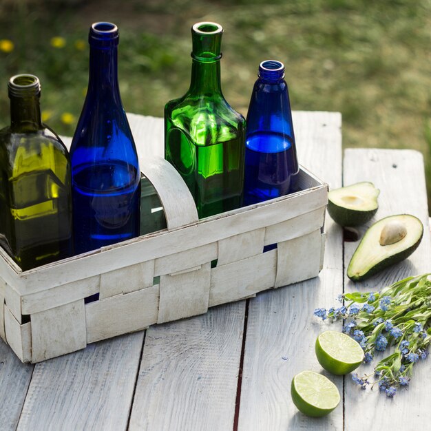 Vier flessen drankjes in een witte mand en fruit op de witte tafel