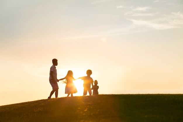 Vier gelukkige kinderen spelen bij zonsondergang, ze springen en houden hun handen vast