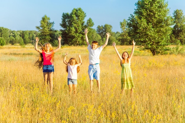 Vier gelukkige mooie kinderen rennen spelend samen bewegend op de mooie zomerdag