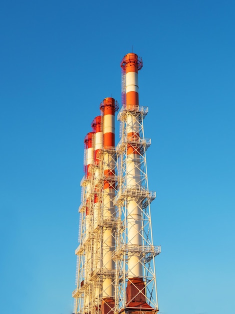 Vier industriële schoorstenen tegen een blauwe lucht