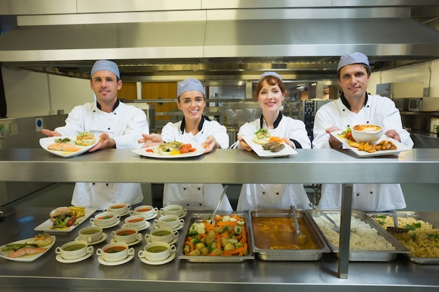 Foto vier jonge chef-koks die platen tonen