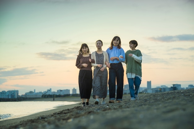 Vier jonge vrouwen die in de schemering langs de zee lopen