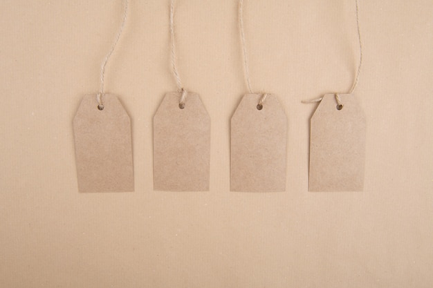 Vier labels van gerecycled kraftpapier die aan een touw op kraftpapier hangen. Plat leggen