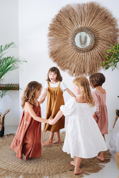 Foto vier meisjes draaien hand in hand. kinderen spelen samen in een helder huis.