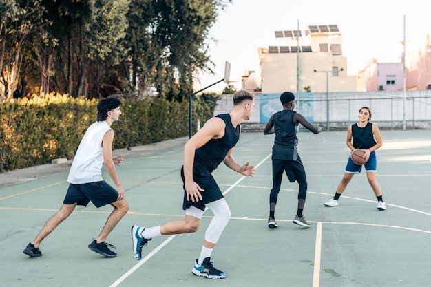 Vier multiculturele vrienden die buiten basketballen op een stedelijk hof