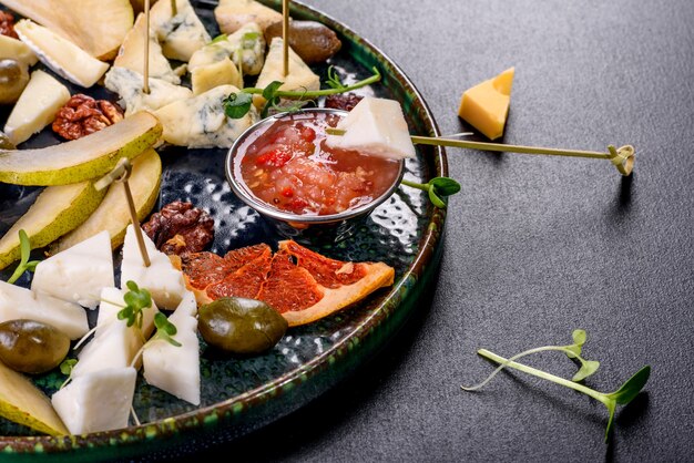 Vier soorten kaas snijden: geiten, parmezaan, camembert en brie met plakjes peer en gedroogde grapefruit en microgreens. Lekker gezond tussendoortje