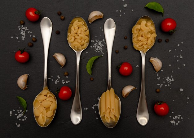 Vier soorten pasta in lepel swith knoflook peper tomaten Flatlay Bovenaanzicht Food Concept foto