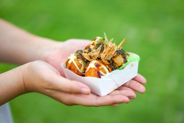 Vier Takoyaki Lokale Japanse octopusvleesbal in de hand met onscherpe achtergrond klaar om te eten