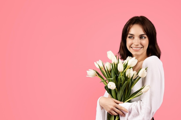 Vier vakantieverjaardag in de lente Blije jonge Europese vrouw met een boeket witte tulpen