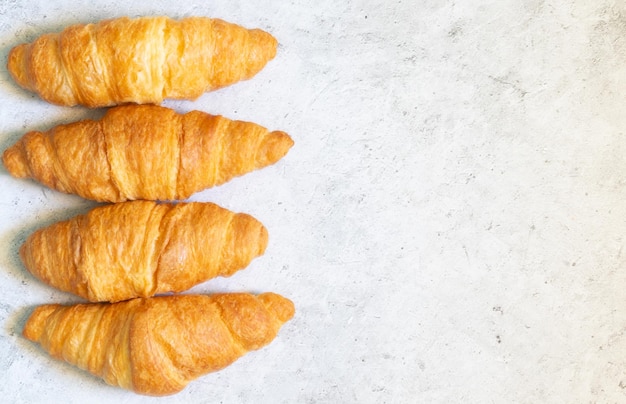 Foto vier verse croissants op een lichte betonnen achtergrond bovenaanzicht met kopieerruimte