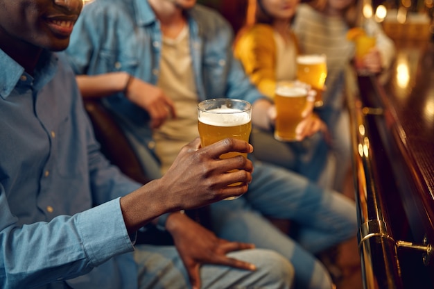 Vier vrienden drinken bier aan het loket in de bar