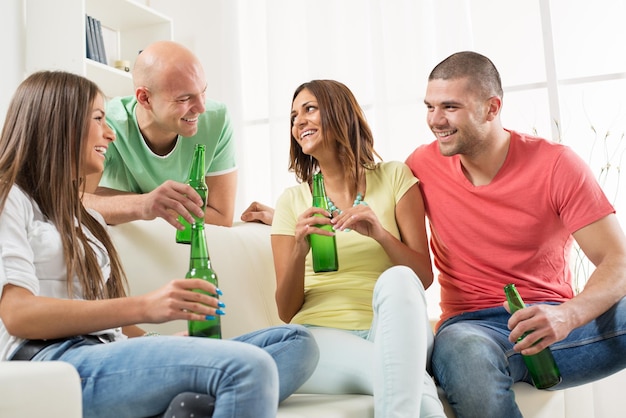 Vier vrienden genieten samen met bier op het huisfeest.