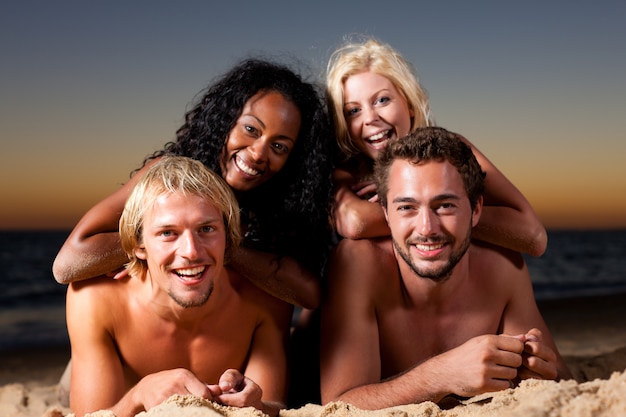 Vier vrienden op het strand met zonsondergang